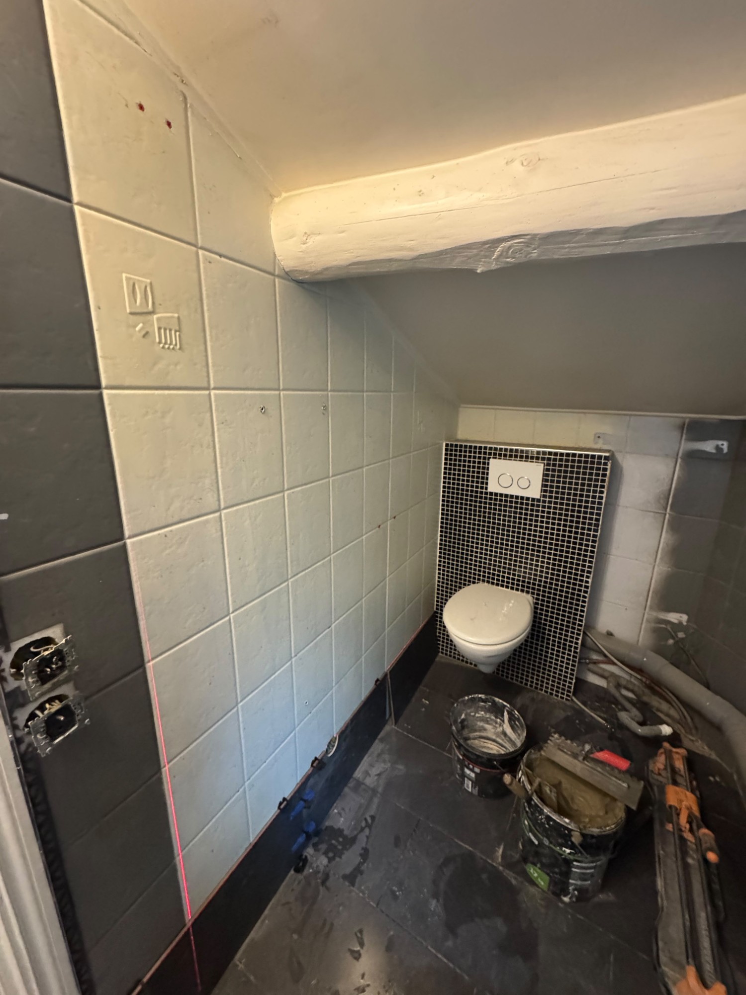 Pose de faïence murale blanche dans une salle de bain, alignement réglé au laser